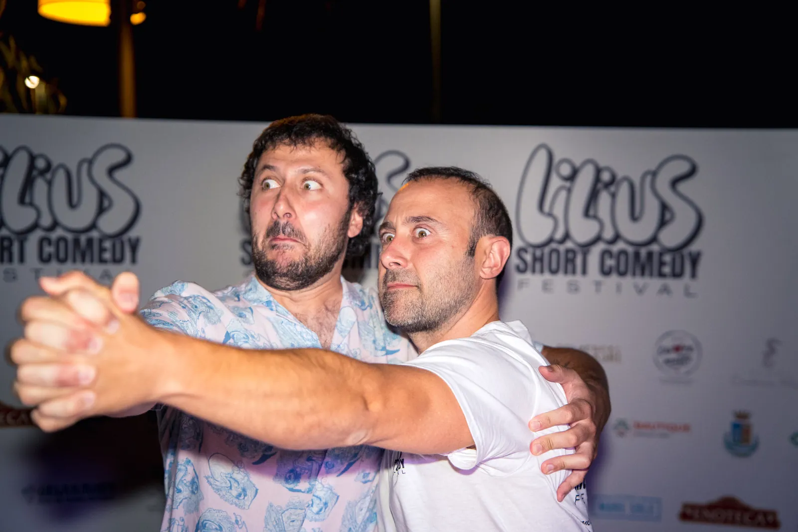 Due spettatori in posa buffa da tango, con espressioni comiche esagerate, davanti al backdrop del Lilius Short Comedy Festival