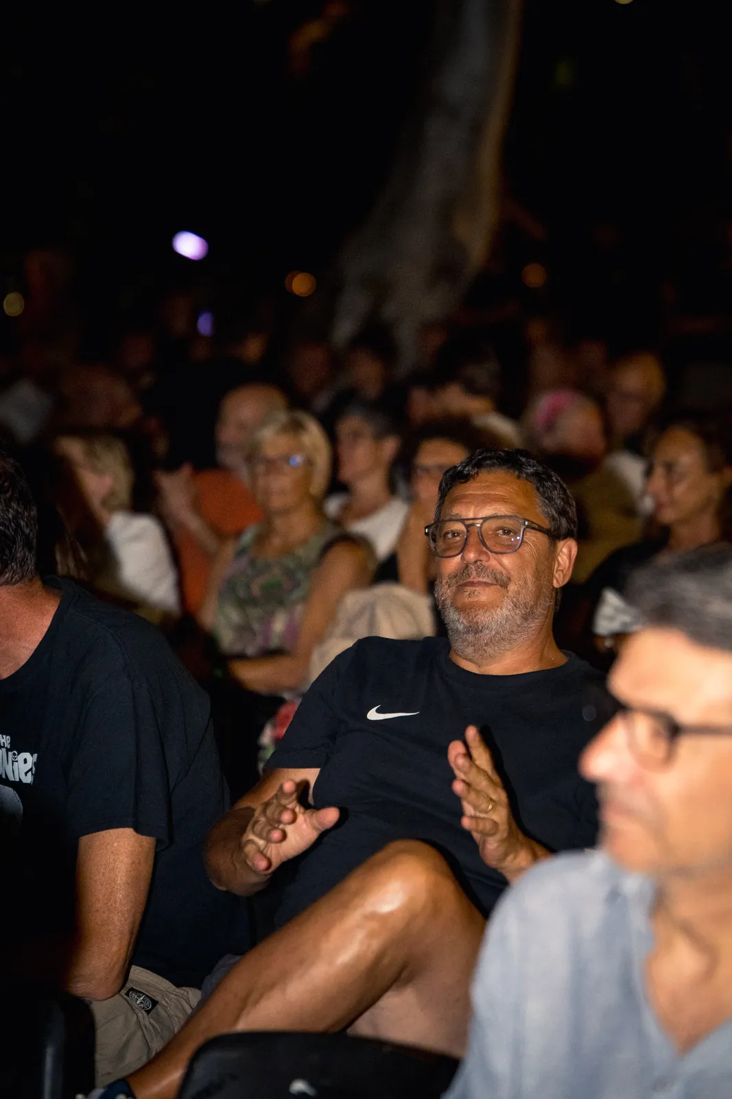 Uno spettatore ripreso a mezzo busto, con il pubblico sfocato alle sue spalle