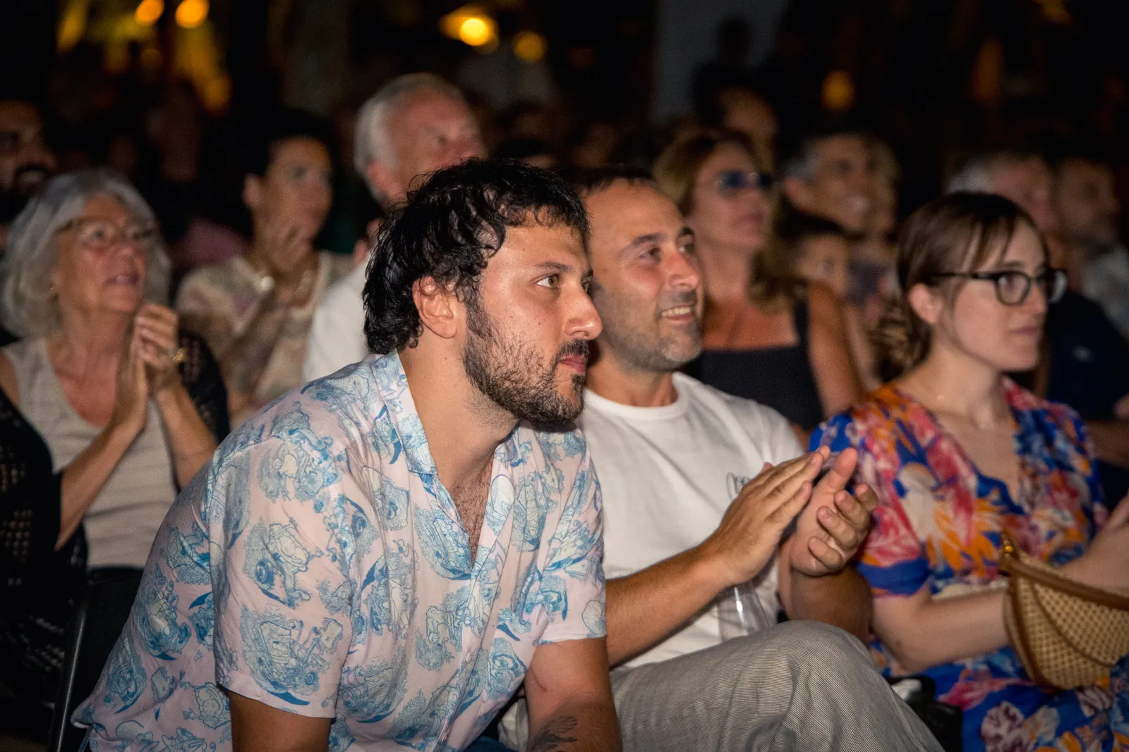 Un gruppo di spettatori applaude da vicino, con i colori vivaci degli abiti in risalto