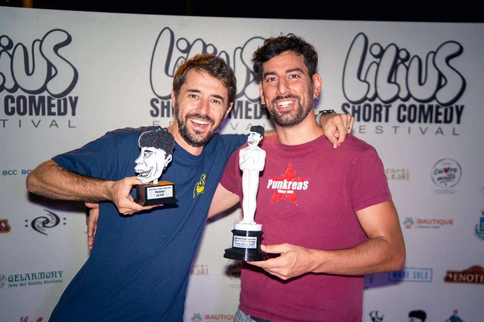 Due vincitori abbracciati al photo-wall, ciascuno con il proprio trofeo: la statuetta del Premio Lilius e quella del Miglior Cortometraggio